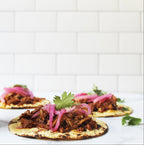 Jar of Salsaology Pibil sauce with tacos on a white background